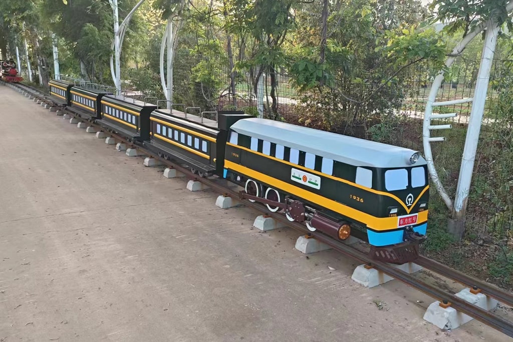 Traditional green train design track miniature train ride operating on rails, suitable for amusement parks and theme parks.