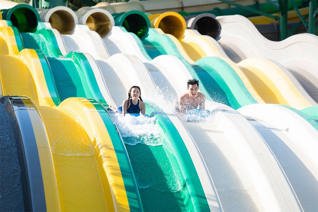 Visitors sliding down colorful water slides at a popular water park in Southeast Asia, captured in action.