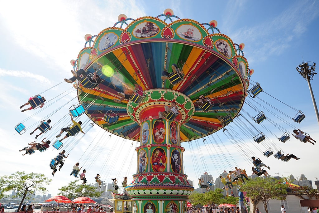 Families enjoying swing carousel ride together in amusement park