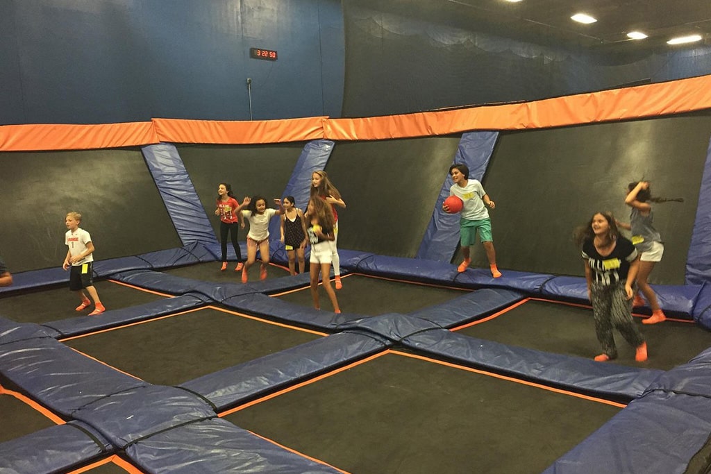 Adults bouncing and having fun in a large indoor trampoline park, enjoying fitness and excitement.
