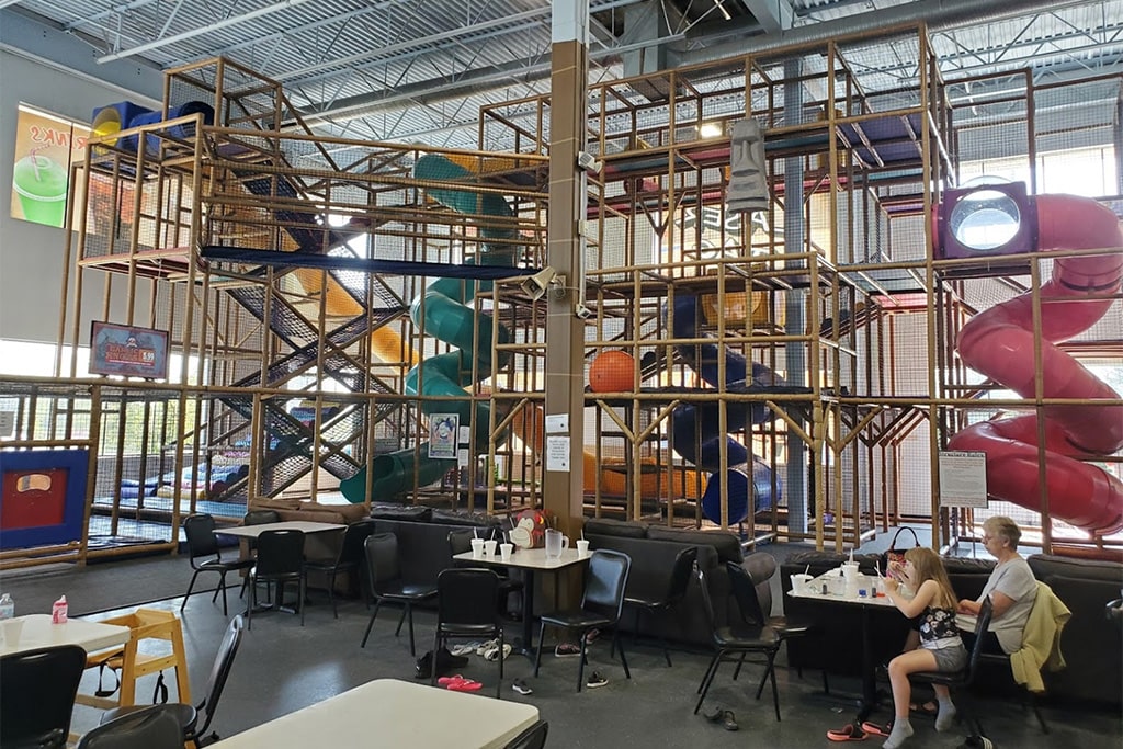 Adults relaxing in a comfortable lounge area within an indoor playground, enjoying a break after fun activities.
