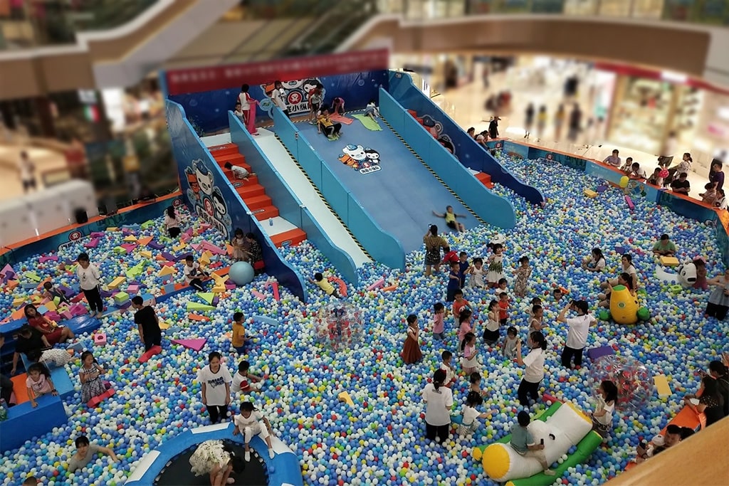 A busy indoor playground in a shopping mall where parents and children are playing, showing the strong business potential of indoor playgrounds.