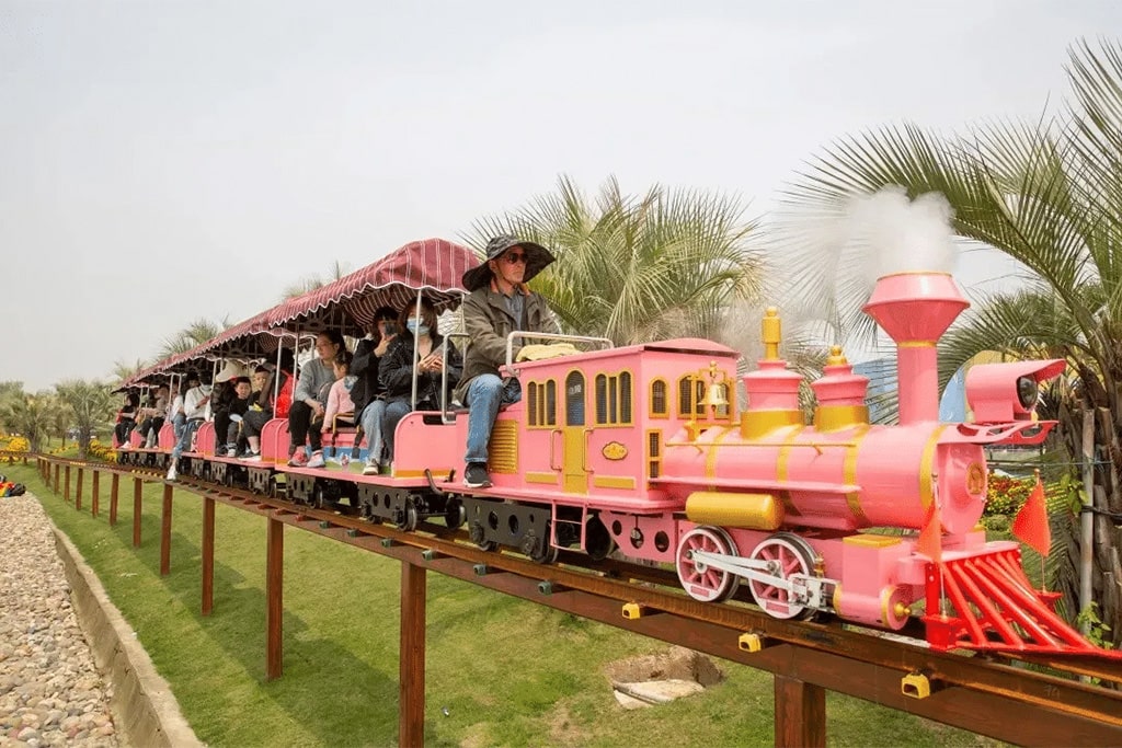 Rideable train with elevated track about one meter above ground in a busy amusement park