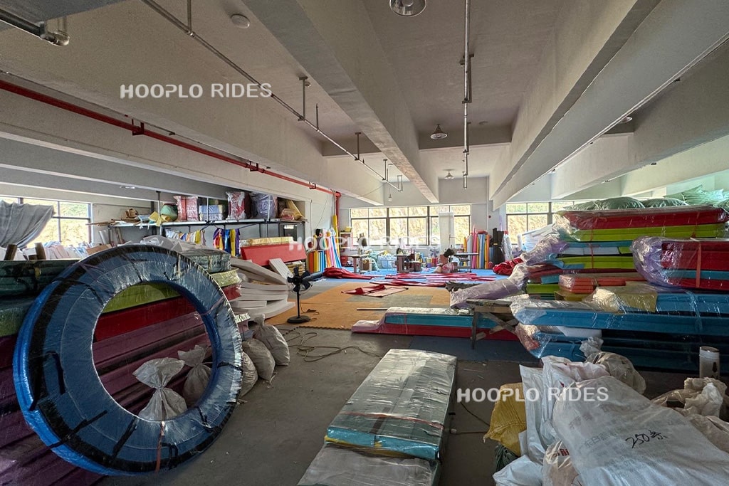 Indoor playground fabric cutting workshop showing precision production process