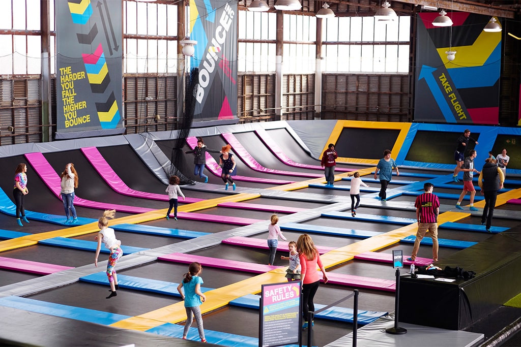 A large trampoline park with many adults enjoying their time, jumping and having fun in a vibrant and energetic environment.