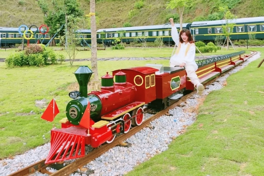 Tourist taking a photo while sitting on a stationary rideable train in an amusement park