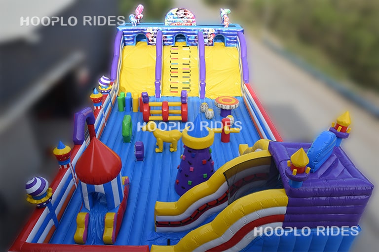 Side view of the Fixies inflatable castle showing the overall structure, slide section, and themed artwork.