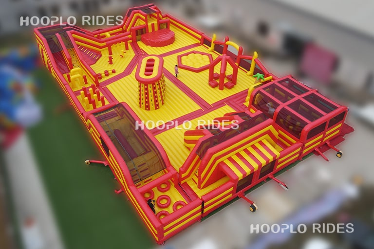 Rear view of the Mega Inflatable Obstacle Course Park with obstacle mazes, elevated platforms, and multiple adventure play zones