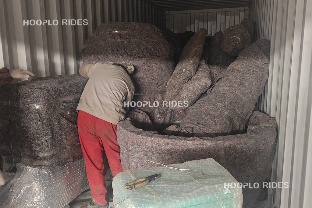 Workers carefully packing small components of the self-controlled airplane ride with protective wrapping