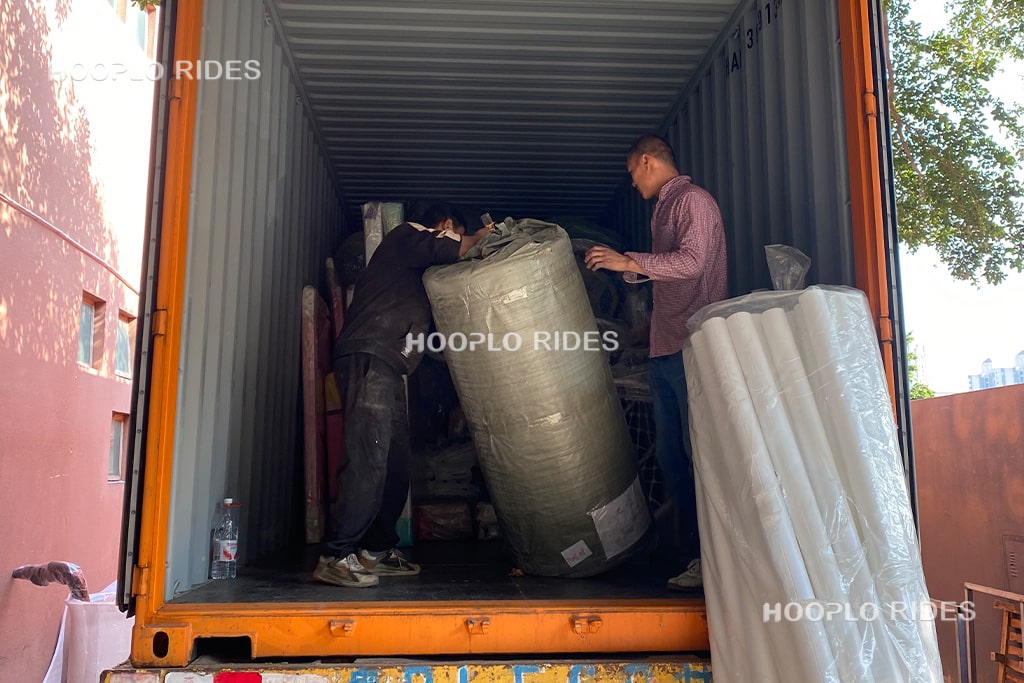 Workers loading packed indoor soft play playground equipment into a shipping container at the factory