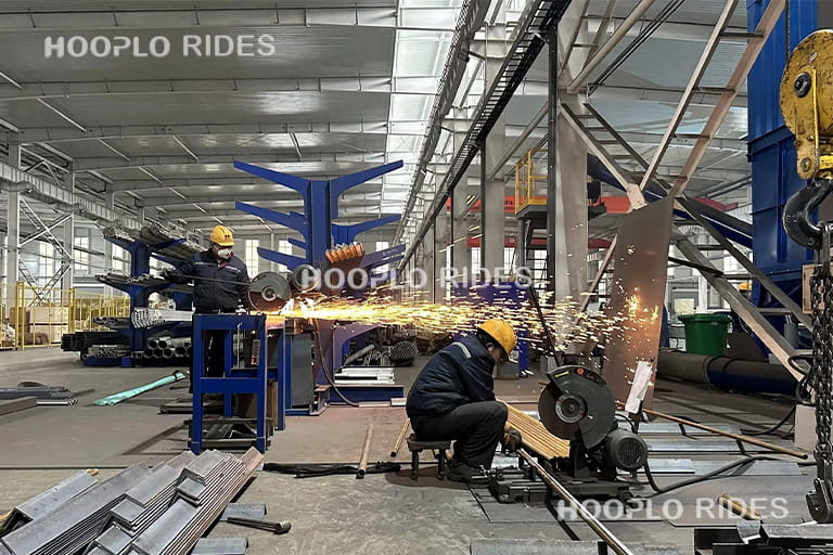 Workers welding the steel structure of a pirate ship ride in a professional amusement ride manufacturing workshop