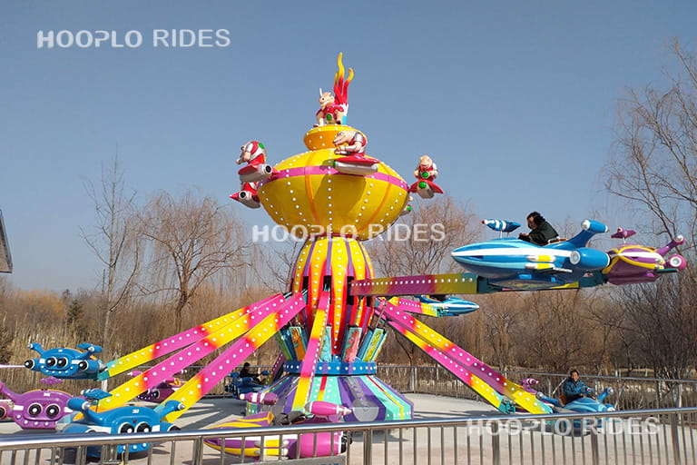 Classic self-control plane ride operating in a domestic theme park with colorful rotating plane cabins and central tower structure.