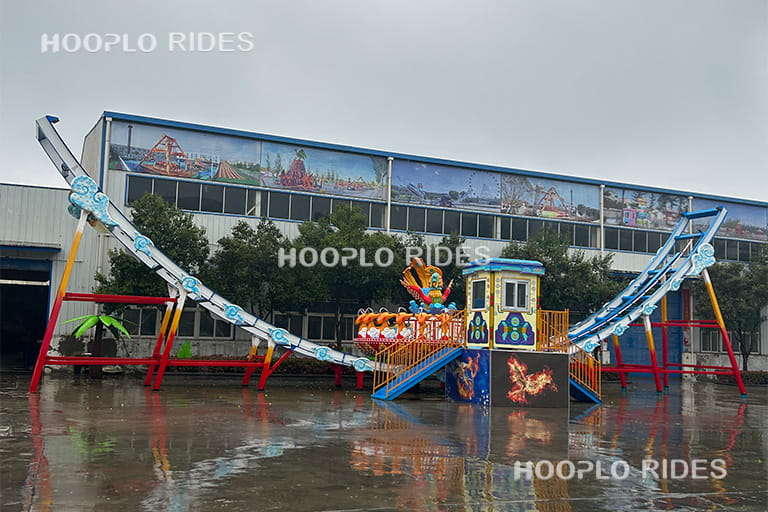 24 seats Disk'O ride installed in an amusement park, featuring a large rotating platform on a curved track.