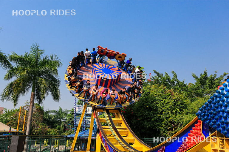24 seats Disk'O ride operating in an amusement park, showing the rotating disk moving along the curved track with riders.