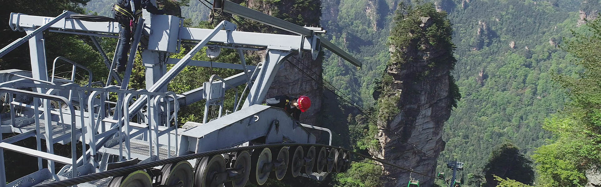 Workers installing a scenic cable car system at a tourist attraction during an amusement ride installation project