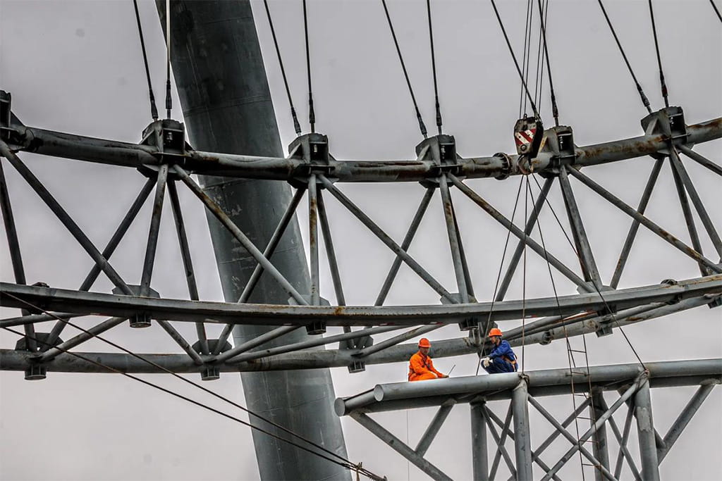Two workers installing a Ferris wheel together as part of an amusement ride installation project
