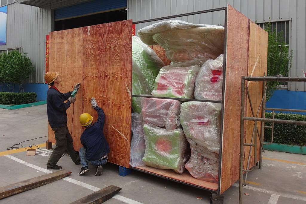 Factory workers gathering packed amusement ride components and preparing them for wooden crate loading, representing professional packing support before shipping