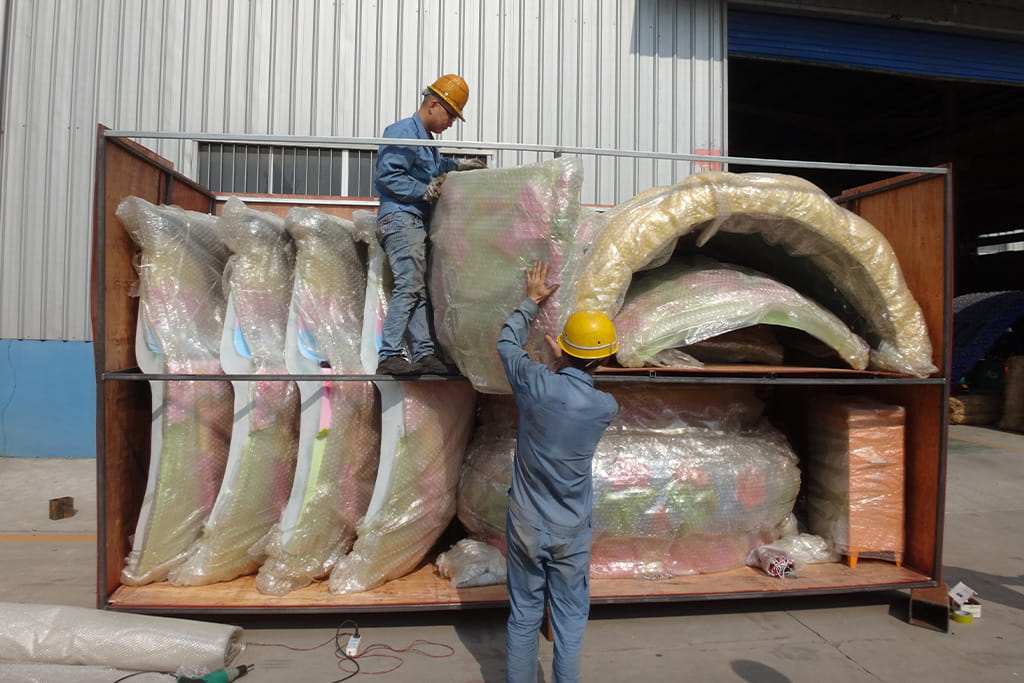 Factory workers carefully packing amusement ride components to ensure safe transportation
