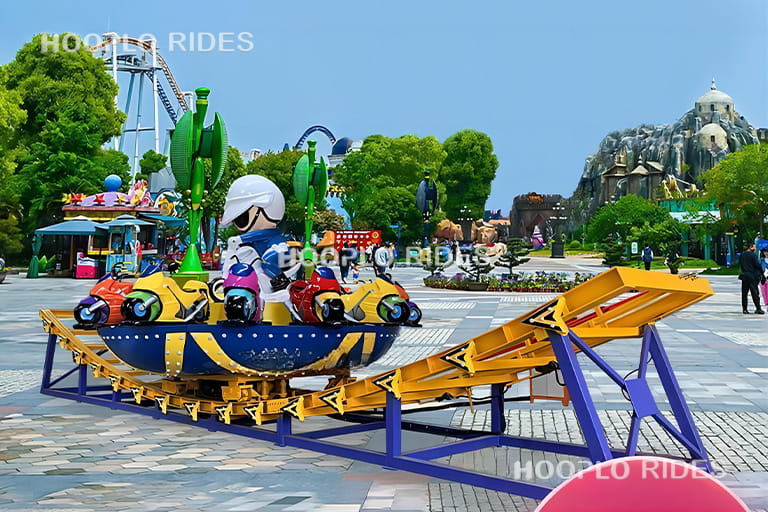 Mini Disk'O ride operating in an amusement park with riders enjoying the spinning and sliding motion along the curved track.