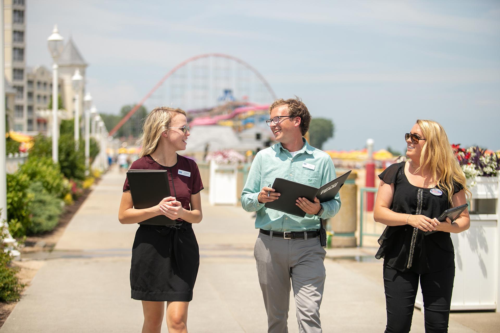 Amusement park manager reviewing ride operations, with visitors enjoying attractions and a spinning chair ride illuminated at dusk.